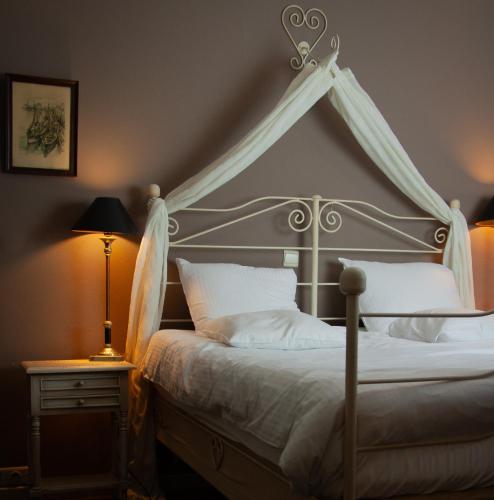 een slaapkamer met een hemelbed met witte kussens bij Hotel De Hofkamers in Oostende