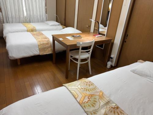 a room with three beds and a wooden table with a chair at 池袋House3F Cozy for 1-3 guests in Tokyo