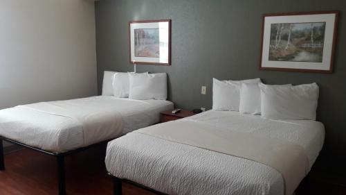 two beds in a hotel room with white sheets at Best Studio Inn Homestead (Extended Stay) in Homestead