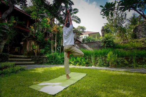 a man doing a handstand on a mat in the grass at Dewangga Ubud in Ubud
