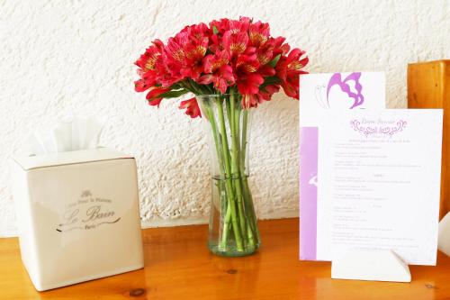 a vase filled with red flowers sitting on a table at Hacienda Panoaya in Amecameca de Juárez