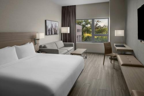 a hotel room with a large white bed and a couch at AC Hotel by Marriott Boston Cambridge in Cambridge