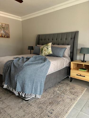 a bedroom with a large bed with a gray headboard at Sebeshong Guest House - Moletjie in Ga-Komape