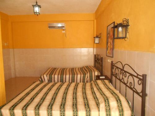 two beds in a room with yellow walls at Rincón del Ángel in Villahermosa