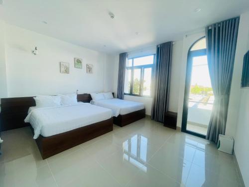 a bedroom with two beds and a large window at Amazon Hotel in Phước Hậu (1)
