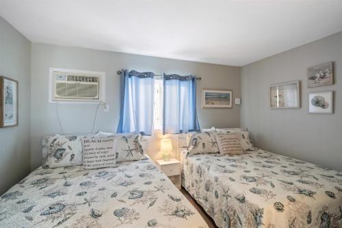 a bedroom with two beds and a window with blue curtains at 6701 Atlantic Ave, Unit 301 in Wildwood Crest