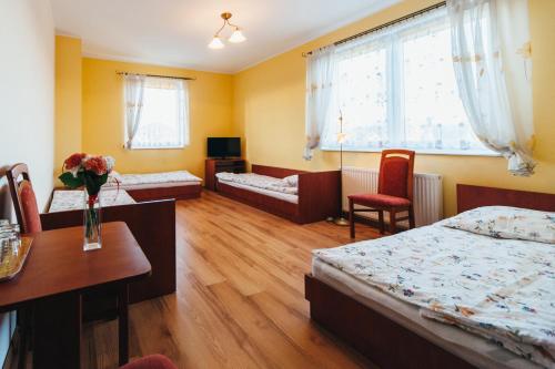 a hotel room with two beds and a table and chairs at Willa Promyk in Gdańsk