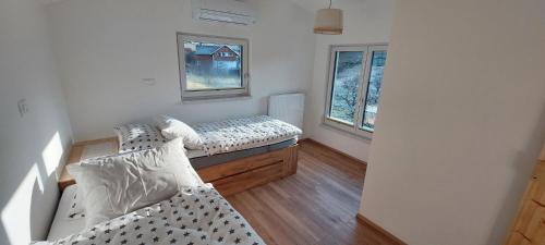 two beds in a room with two windows at Apartments AlpRoza in Zgornje Gorje