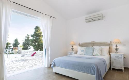 a white bedroom with a bed and a sliding glass door at Villa Asteri in Vlachopoulátika