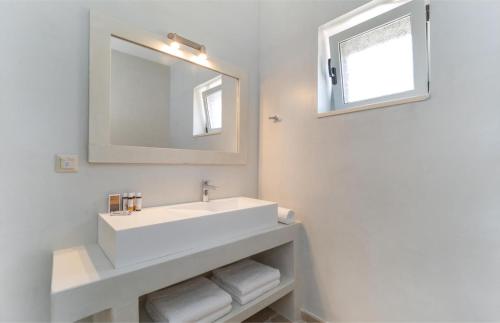 a white bathroom with a sink and a mirror at Villa Moundela in Katsimátika