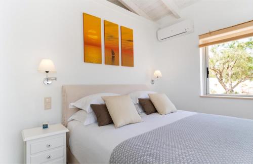 a white bedroom with a bed and a window at Villa Moundela in Katsimátika
