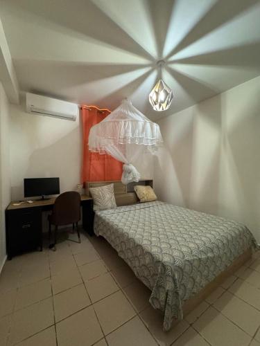 a bedroom with a bed and a desk with a computer at Belle maison équipé avec piscine in Mamoudzou