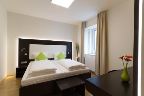 a bedroom with a bed and a table with a vase of flowers at sevenDays Hotel BoardingHouse Mannheim in Mannheim