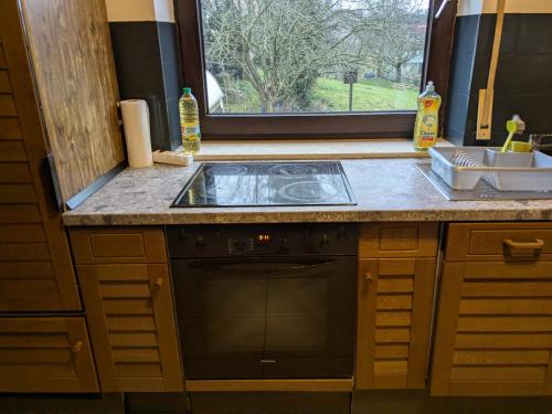 a kitchen with a stove and a sink and a window at Pension Heller in Odelzhausen