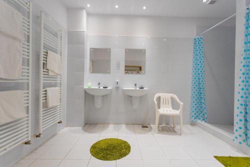 a bathroom with two sinks and a white chair at Green Hostel in Sfântu-Gheorghe