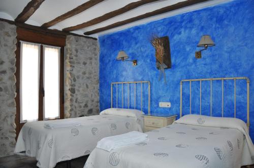 two beds in a room with blue walls at Hotel Rural Verdeancho in Belorado