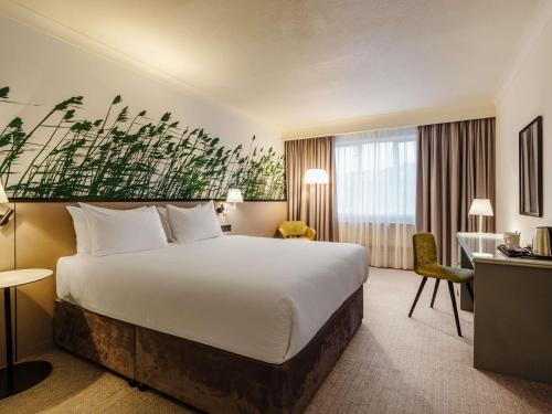 a hotel room with a large bed and a desk at Mercure Daventry Court Hotel in Daventry