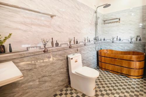 a bathroom with a toilet and a wooden tub at Hidden Valley Eco Retreat Trang An in Ninh Binh