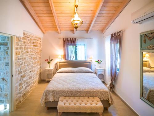a bedroom with a bed and a brick wall at Olive Cottage in Petrátika