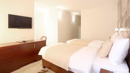una camera d'albergo con due letti e una TV a schermo piatto di Hotel Park a Vogošća