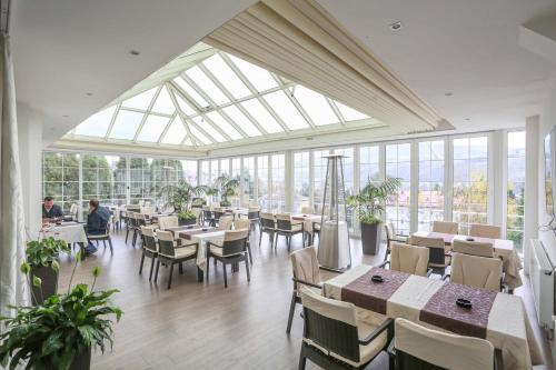 una sala da pranzo con tavoli, sedie e finestre di Hotel Park a Vogošća