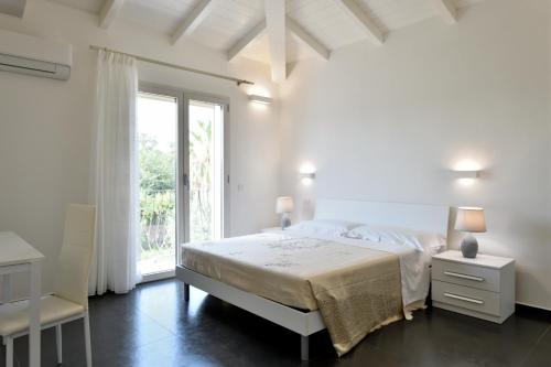 a white bedroom with a bed and a window at Sa Omu Bianca in Tortolì