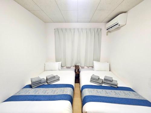 two beds in a small room with a window at Fuji Flat 新大久保駅から徒歩20秒 新宿駅も徒歩15分 有名レストラン多数 歌舞伎町も歩いて行けます in Tokyo