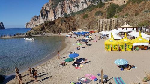 a group of people on a beach with umbrellas at B&B Quintino Sella in Iglesias