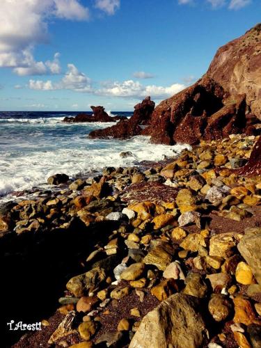 a rocky beach with the ocean and the waves at B&B Quintino Sella in Iglesias