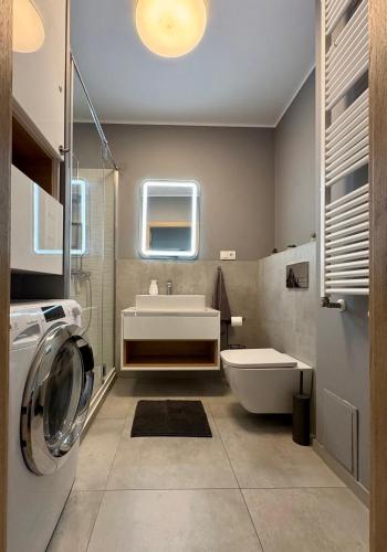 a bathroom with a sink and a washing machine at Apartamenty FilGood in Wałcz