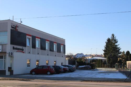 a building with cars parked in a parking lot at Hotel 1 in Płock