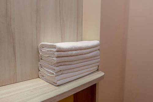 a stack of white towels sitting on a shelf at Avtar new delhi railway station in New Delhi