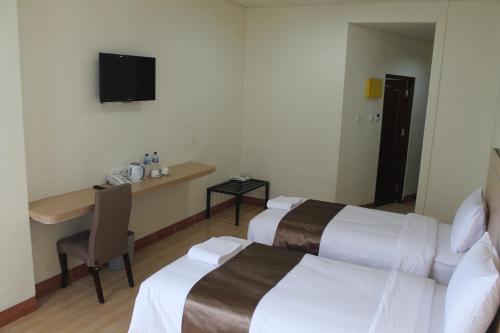 a hotel room with two beds and a table and a television at Revayah Hotels in Ruteng