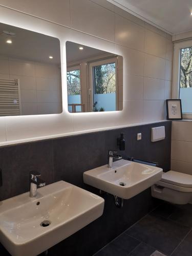 a bathroom with two sinks and a mirror and a toilet at Ferienwohnung am Dörenberg in Georgsmarienhütte