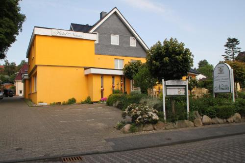 a yellow building with a sign in front of it at Hotel Neuses in Cuxhaven