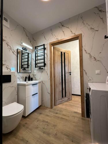 a bathroom with a toilet and a sink and a door at Apartament w centrum 5A in Iława