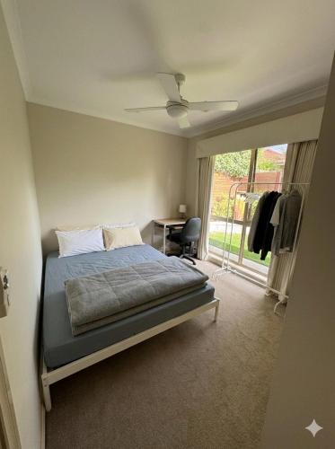 a bedroom with a bed and a desk and a window at Homestay - Room for Rent Bundoora in Melbourne