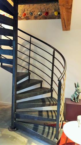 a black spiral staircase in a living room at Le kaolin in Bully