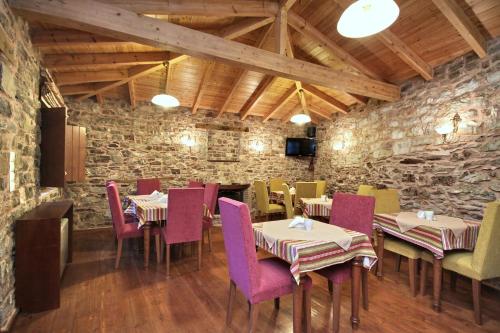 un restaurante con mesas y sillas y una pared de piedra en Archontiko, en Andrítsaina