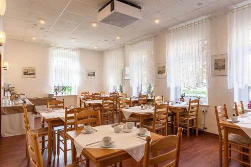 jadalnia ze stołami, krzesłami i oknami w obiekcie Hotel Burgk w Dreźnie