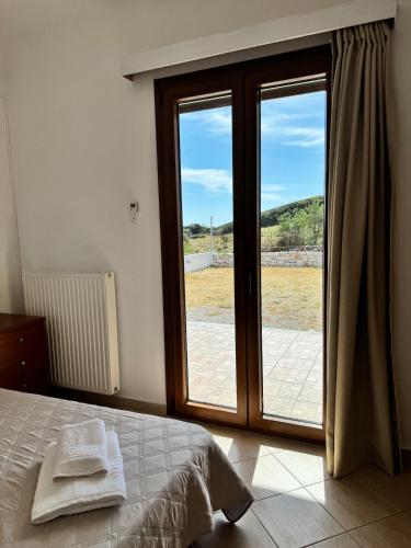 a bedroom with a bed and a sliding glass door at Limnes Seaside Retreat in Naxos Chora