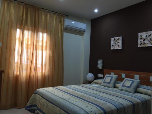 a bedroom with a bed with a blue blanket and a window at Medina Azahara in El Higuerón