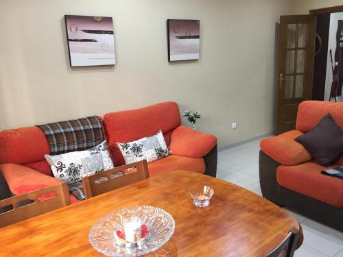 a living room with orange couches and a wooden table at Medina Azahara in El Higuerón
