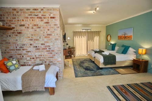 a bedroom with two beds and a brick wall at Hadassa Guest House in Otjiwarongo