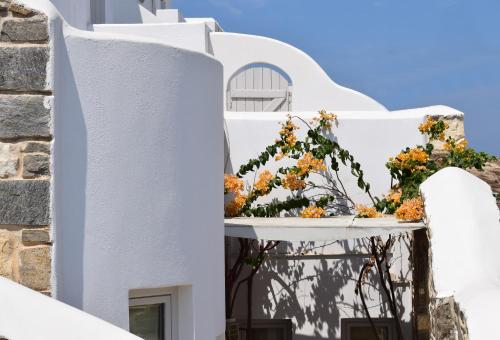 a white building with flowers on a balcony at Kanale's Rooms & Suites in Naousa