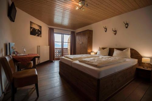 Schlafzimmer mit einem Bett, einem Tisch und einem Fenster in der Unterkunft Hotel Karwendelblick in Urfeld