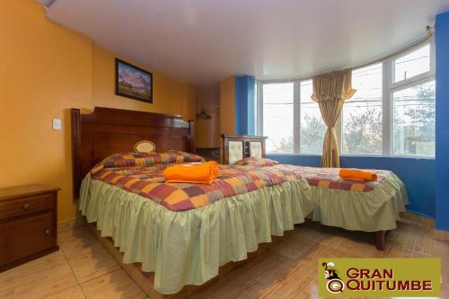 a bedroom with a bed with orange pillows on it at Hotel Gran Quitumbe in Quito