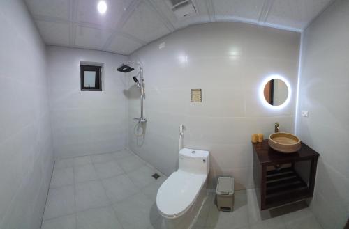 a white bathroom with a toilet and a sink at Tam Coc Natura Hotel in Văn Lâm