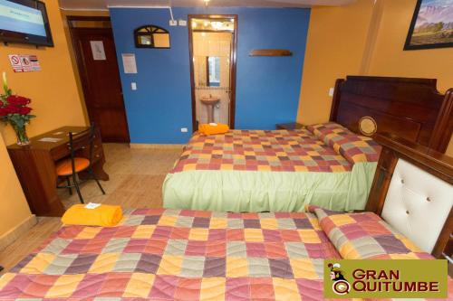 a hotel room with two beds and a table and a desk at Hotel Gran Quitumbe in Quito