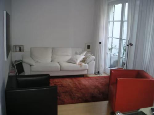 a living room with a white couch and a red chair at Zum oberen Schulhof in Konstanz
